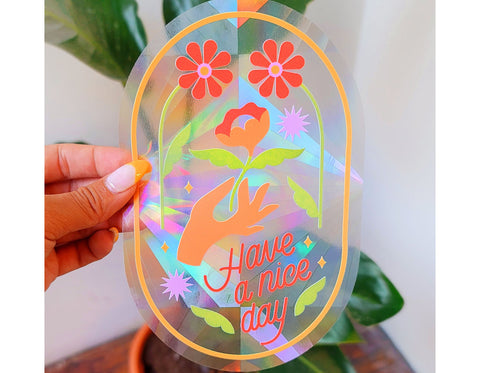 suncatcher sticker text reads have a nice day has hand holding flowers