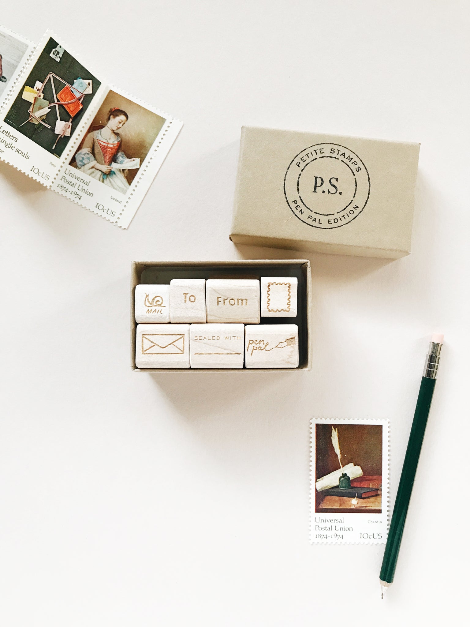 a set of 7 petite rubber stamps- housed in a kraft paper box. hand drawn images include: snail mail, to, from, rectangle blank postage stamp, envelope, sealed with (blank for fill in of your choice) and pen pal.