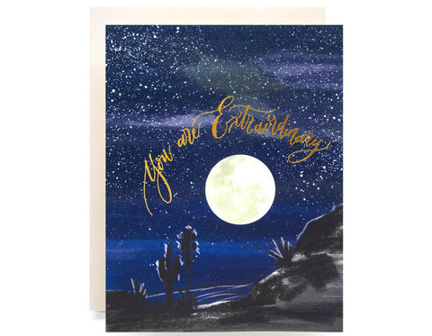 night sky with large moon and desert landscape text reads you are extraordinary in gold foil