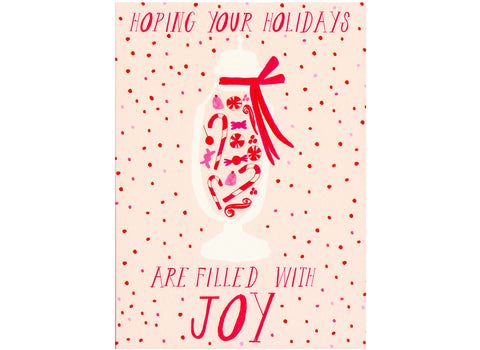 pink background red and pink polka dots. text reads hoping your holidays are filled with joy with a glass container filled with candy