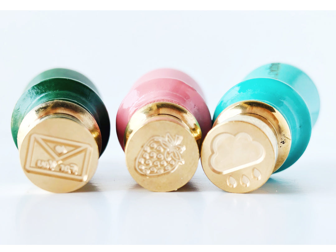 mini brass seals an envelope with a heart and the words for you, a strawberry, and a cloud with raindrops
