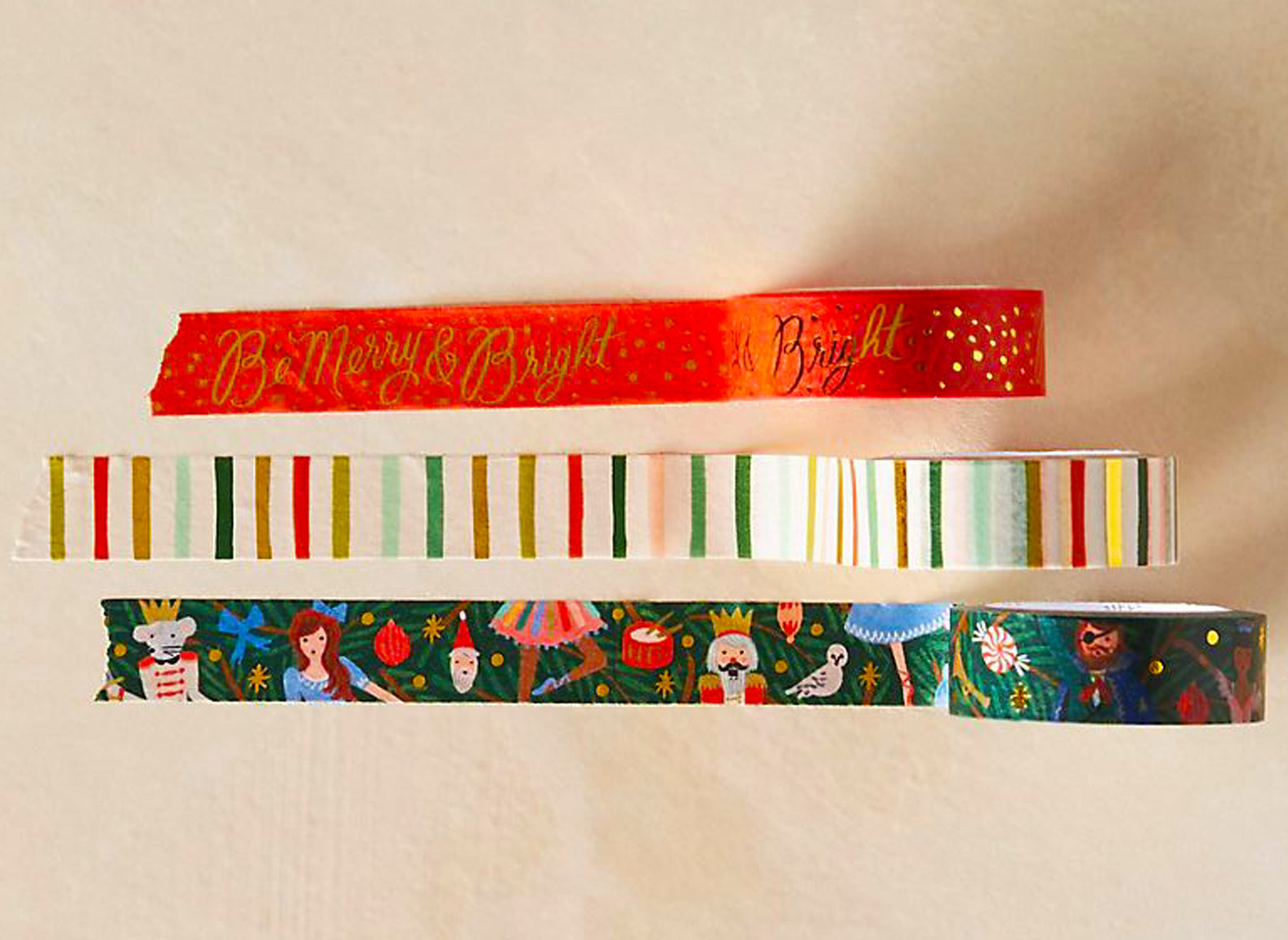 set of three holiday themed washi tapes from rilfe paper co. red backgorund with gold lettering be merry & bright. colorful watercolor stripes, and nutcracker characters.