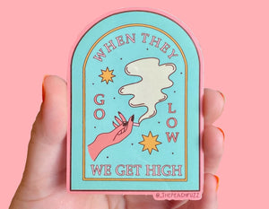 sticker reads when they go low we get high with a pink manicured hand holding a blunt and light blue background